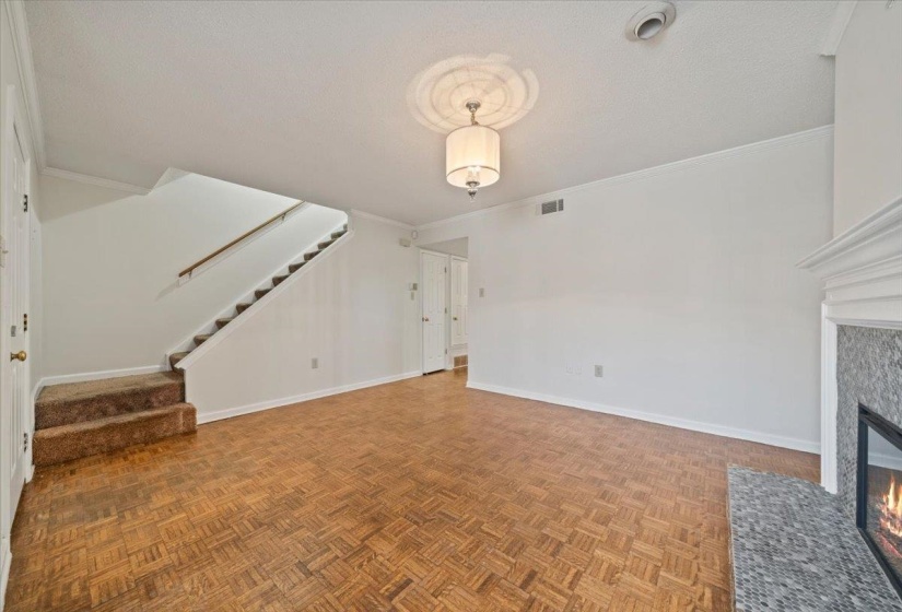 Unfurnished living room featuring crown molding, stairs, a tile fireplace, and a textured ceiling