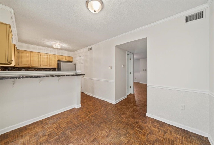 Kitchen with a peninsula, a textured ceiling, dark countertops, crown molding, and refrigerator