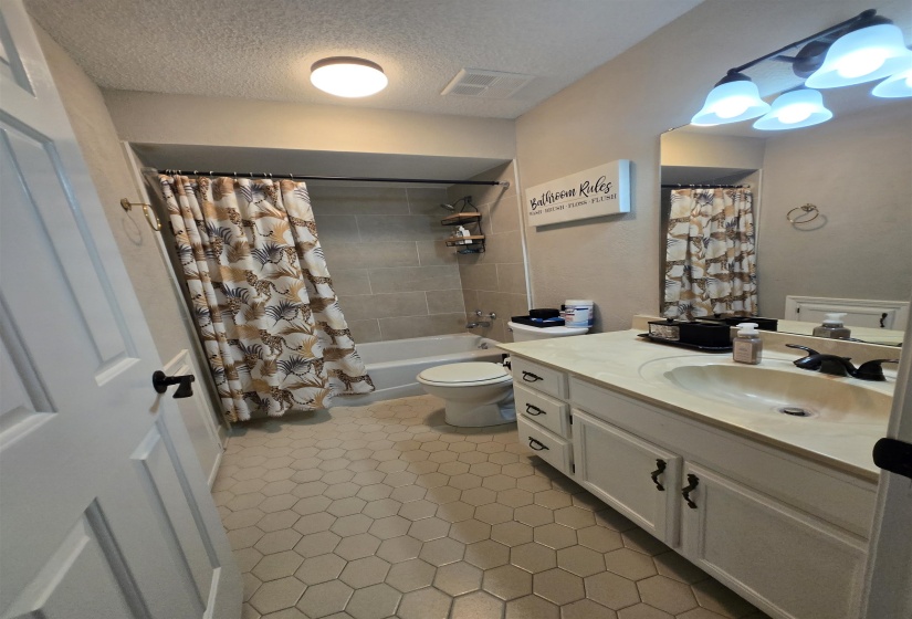 Bathroom with vanity, a textured ceiling, and shower / bath combo with shower curtain