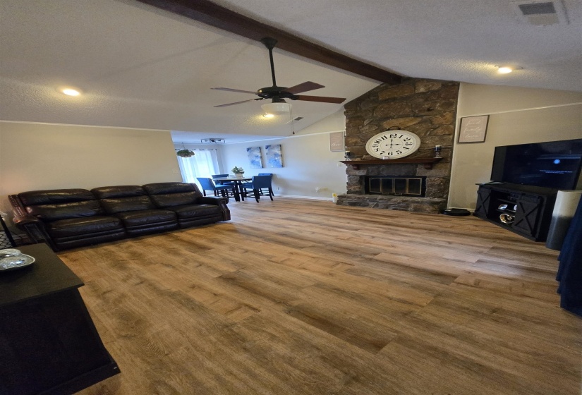 Living area with a fireplace, a textured ceiling, and a ceiling fan