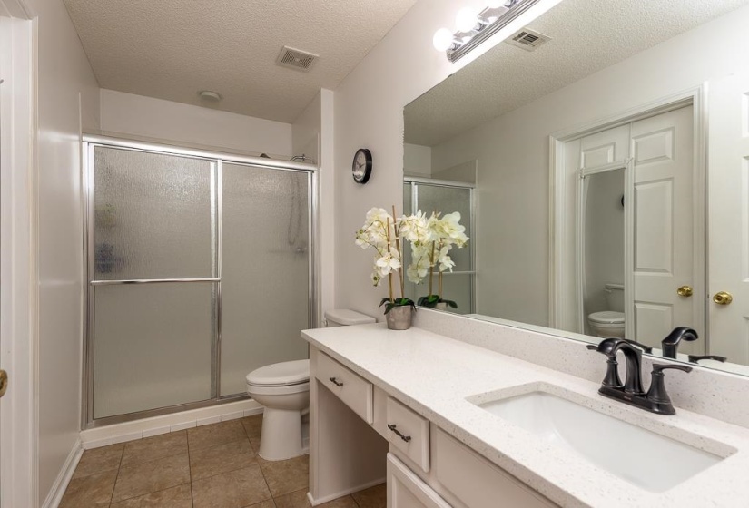 Bathroom with a textured ceiling, vanity, a shower stall, and light tile patterned flooring