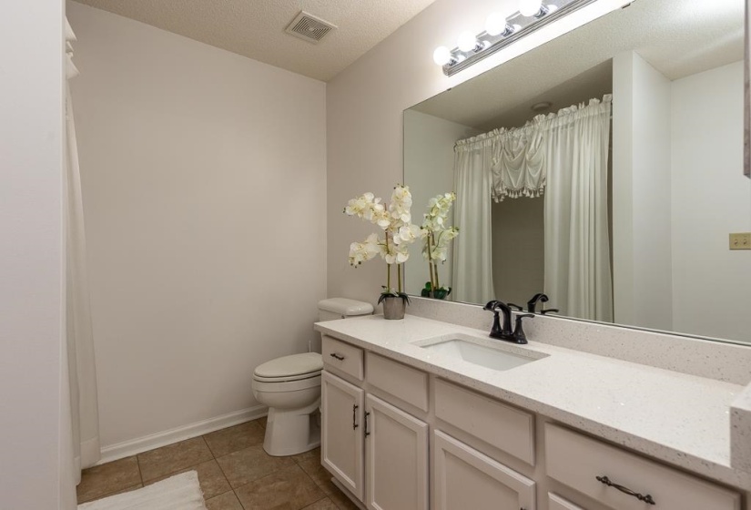 Bathroom featuring vanity, a textured ceiling, a shower with shower curtain, and light tile patterned floors