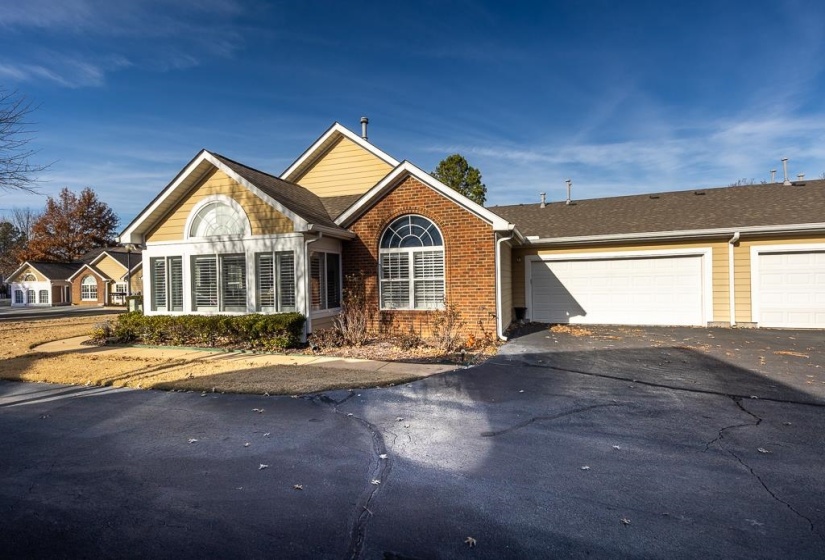 View of front facade with asphalt driveway, brick siding, and an attached garage
