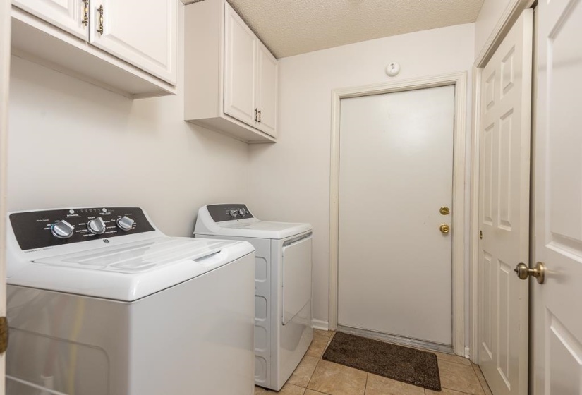 Laundry area featuring a textured ceiling, independent washer and dryer, cabinet space, and light tile patterned floors