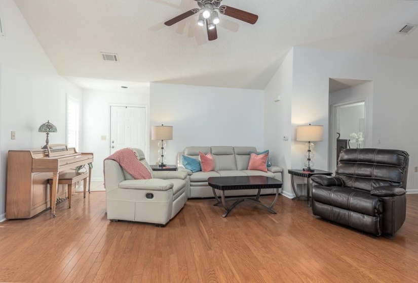 Living area with wood-type flooring, a ceiling fan, and vaulted ceiling