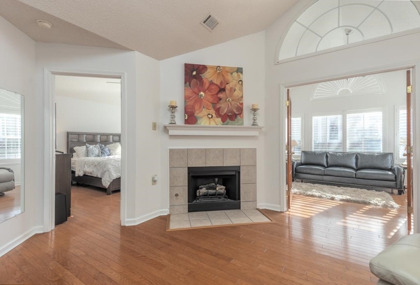 Living area with lofted ceiling, hardwood / wood-style floors, plenty of natural light, and a textured ceiling