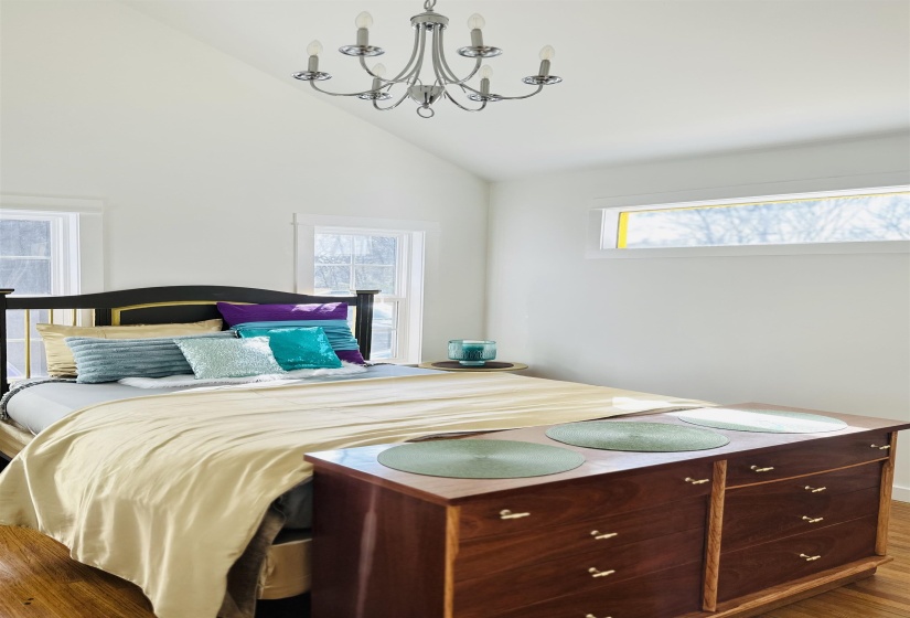 Bedroom with dark wood-style flooring, vaulted ceiling, and hanging lights