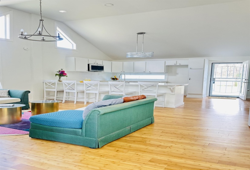 Living area with light wood-type flooring, vaulted ceiling, and a chandelier