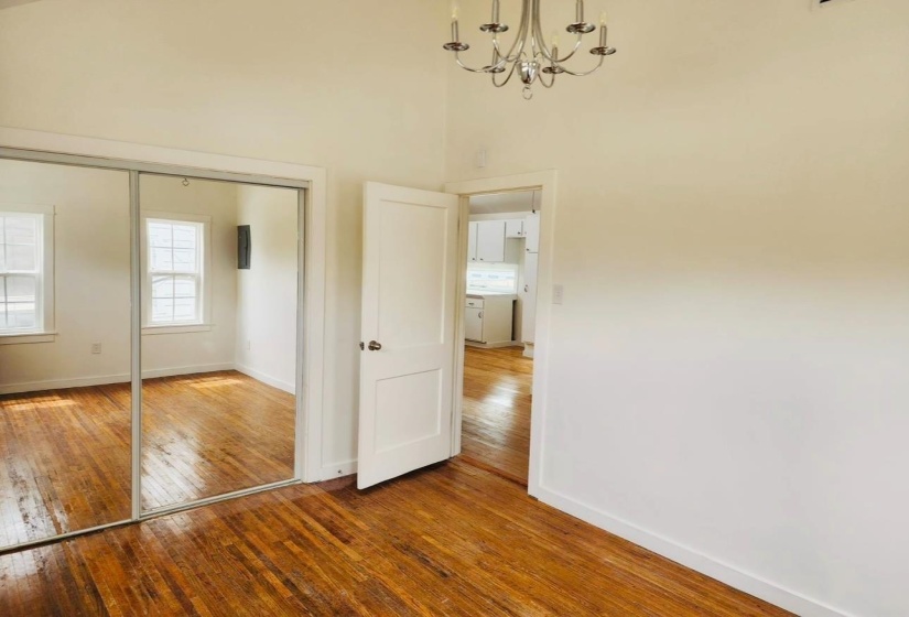 Unfurnished bedroom with hardwood / wood-style flooring, a closet, a chandelier, and a towering ceiling