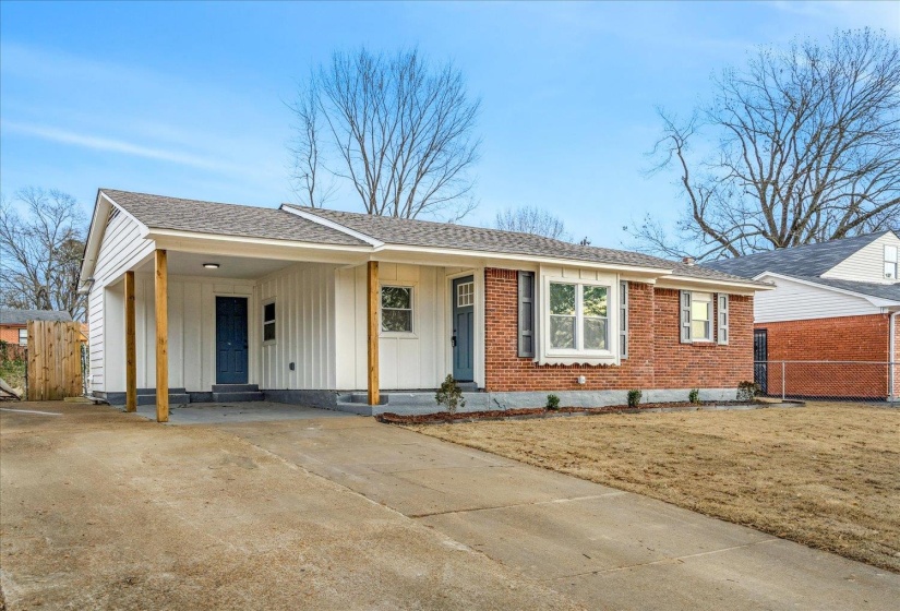 View of front of home with board and batten siding, concrete driveway, a carport, and roof with shingles