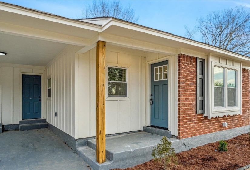 Property entrance with board and batten siding, a porch, and brick siding