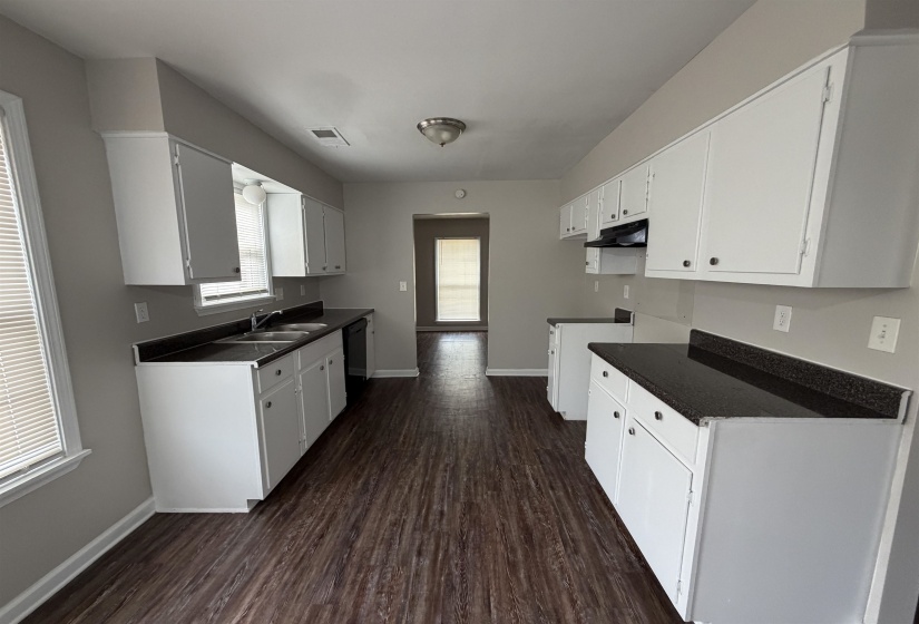 Kitchen with dark countertops, dark wood-style flooring, and white cabinets