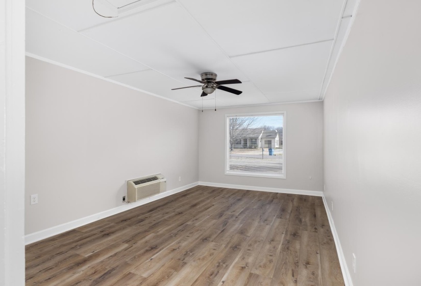 Spare room featuring wood finished floors, crown molding, ceiling fan, and a wall mounted air conditioner