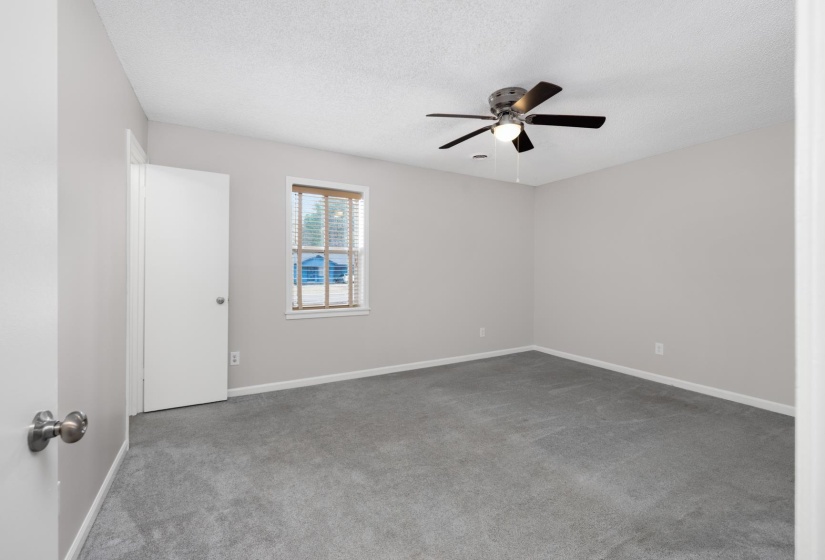Carpeted empty room featuring a textured ceiling and ceiling fan
