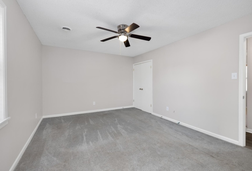 Spare room featuring light colored carpet, ceiling fan, and a textured ceiling