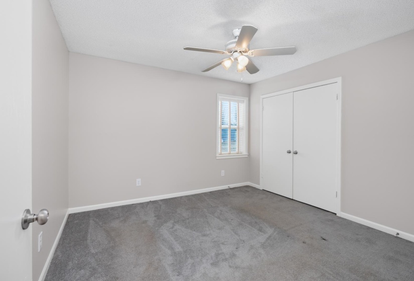 Unfurnished bedroom featuring carpet flooring, a textured ceiling, ceiling fan, and a closet