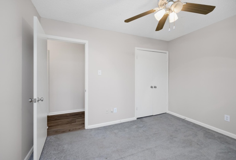 Unfurnished bedroom featuring carpet flooring, a ceiling fan, a closet, and a textured ceiling