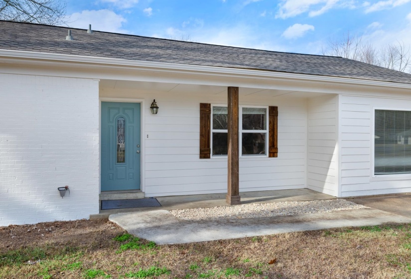 Entrance to property with a porch, a shingled roof, and brick siding