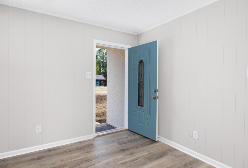 Foyer with wood finished floors, ornamental molding, and wood walls