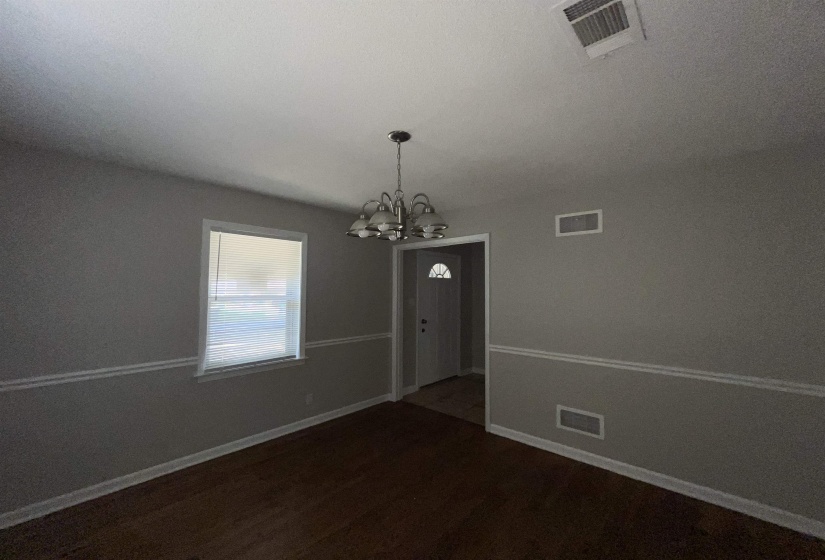 Unfurnished dining area featuring a chandelier and dark wood-style floors