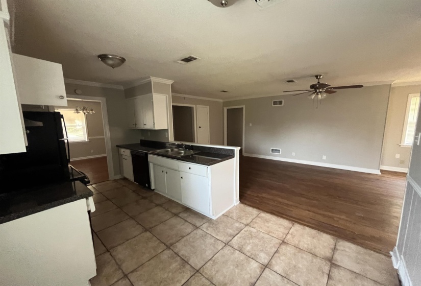 Kitchen featuring white cabinetry, ornamental molding, black dishwasher, a peninsula, and light wood finished floors