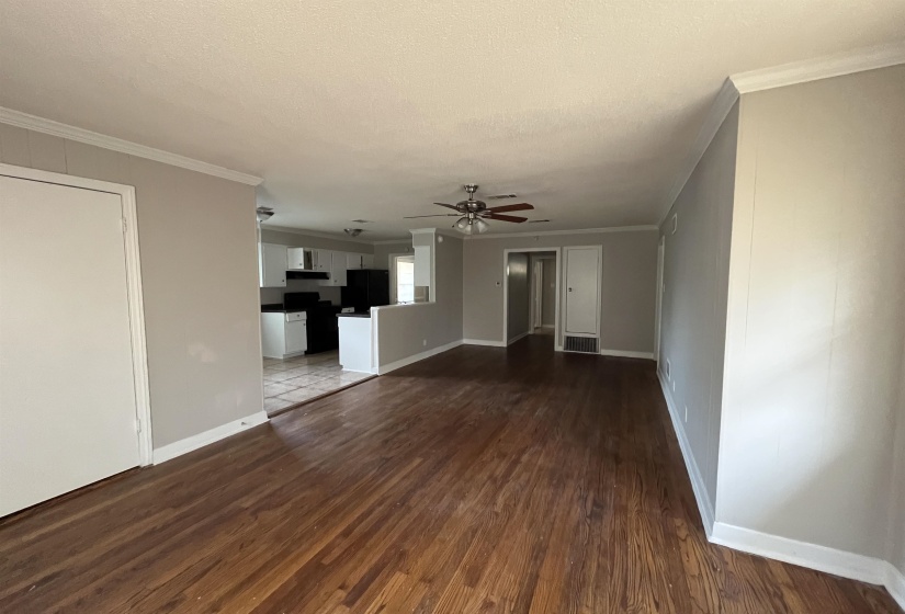 Unfurnished living room with ornamental molding, dark wood finished floors, ceiling fan, and a textured ceiling