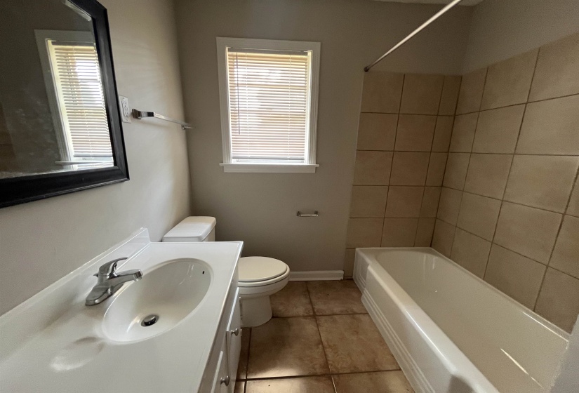 Bathroom with vanity, washtub / shower combination, plenty of natural light, and light tile patterned flooring