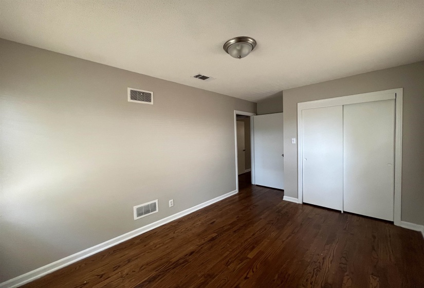 Unfurnished bedroom featuring dark wood-style flooring and a closet