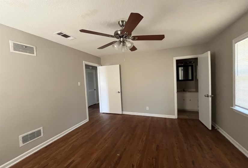 Unfurnished bedroom featuring dark wood-style flooring, ceiling fan, connected bathroom, and a textured ceiling