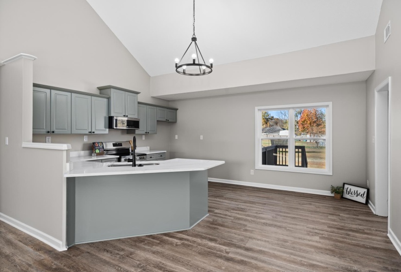 Kitchen with gray cabinetry, dark wood finished floors, high vaulted ceiling, a peninsula, and stainless steel appliances