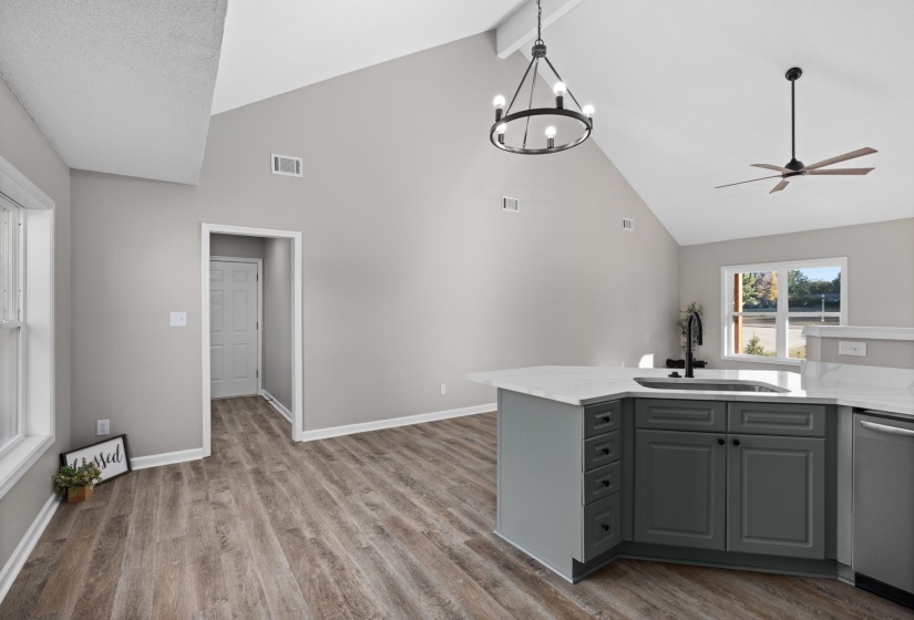 Kitchen featuring gray cabinetry, high vaulted ceiling, light wood-style flooring, dishwasher, and light stone countertops