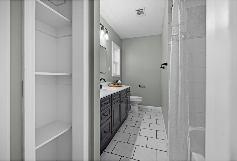 Bathroom featuring vanity, light tile patterned floors, shower / bath combination with curtain, and a closet