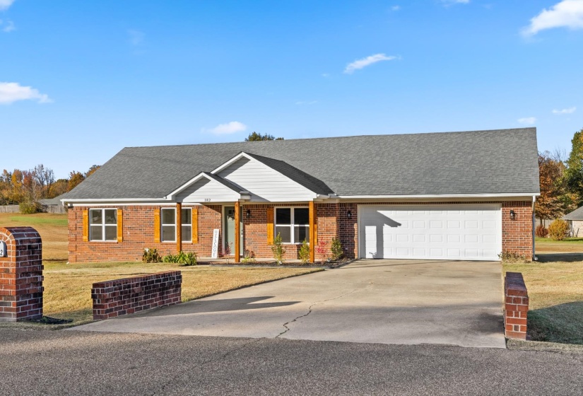 Ranch-style house with a shingled roof, driveway, and brick siding