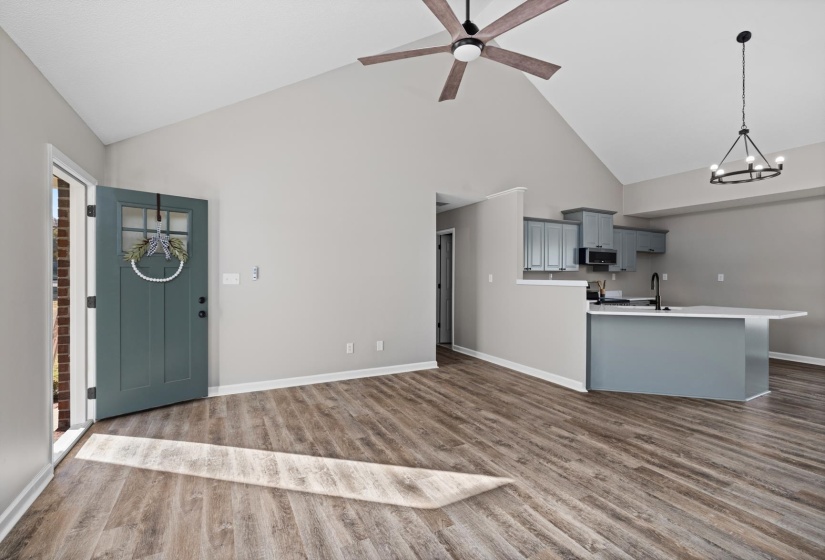 Kitchen with gray cabinetry, high vaulted ceiling, light countertops, a chandelier, and ceiling fan