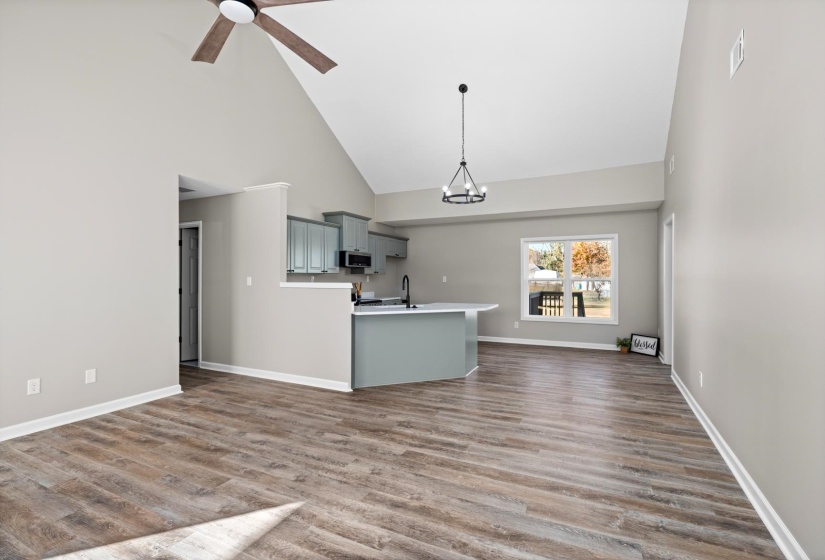 Kitchen featuring gray cabinetry, high vaulted ceiling, light countertops, a chandelier, and open floor plan