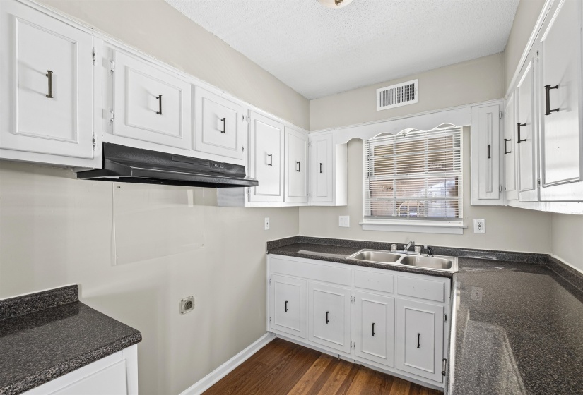 Kitchen featuring white cabinetry, dark countertops, under cabinet range hood, a textured ceiling, and dark wood finished floors
