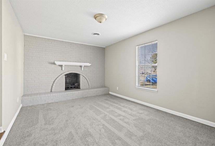 Unfurnished living room with carpet, a brick fireplace, and a textured ceiling
