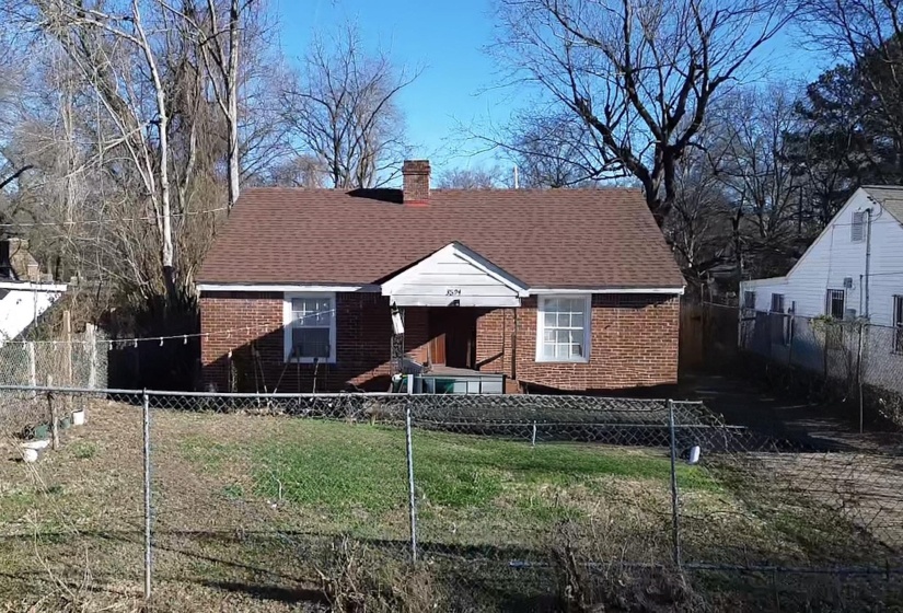 Bungalow featuring a fenced front yard, a chimney, brick siding, and roof with shingles