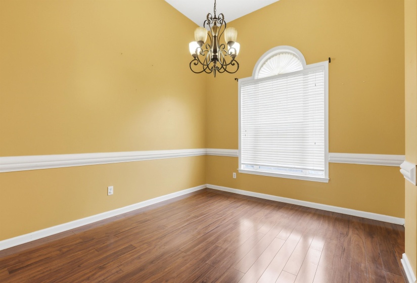 Spare room with wood finished floors, a chandelier, and vaulted ceiling