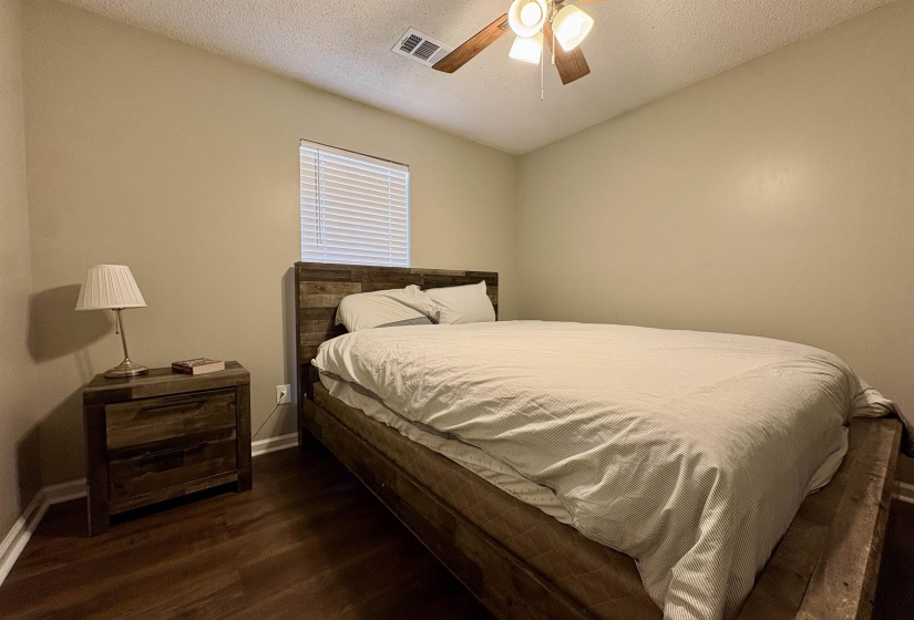Bedroom with a textured ceiling, dark wood-type flooring, and ceiling fan