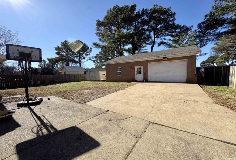 Garage featuring concrete driveway and a shed