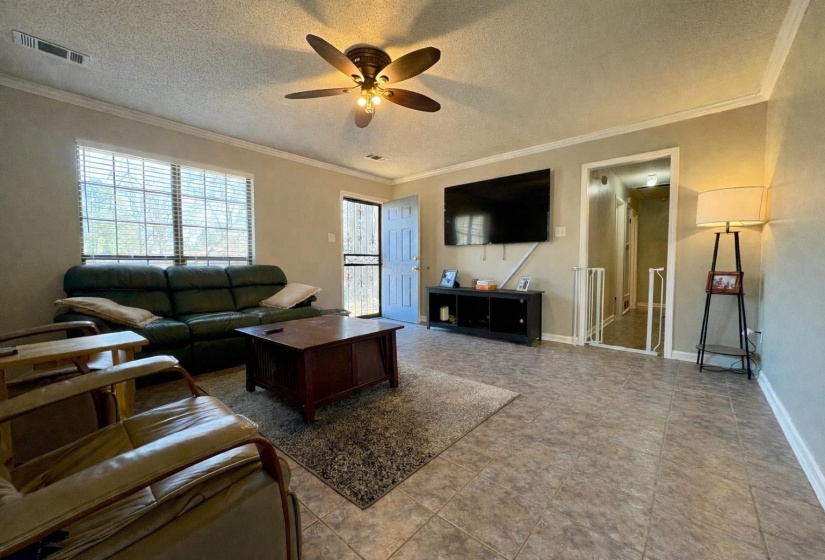 Living area featuring ornamental molding, a textured ceiling, and ceiling fan