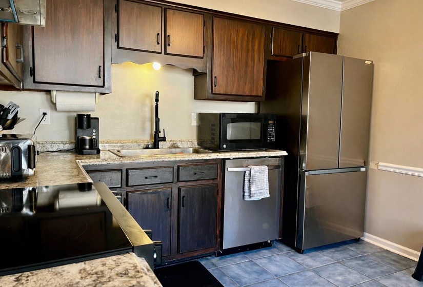 Kitchen featuring light countertops, black appliances, dark brown cabinets, tile patterned flooring, and ornamental molding