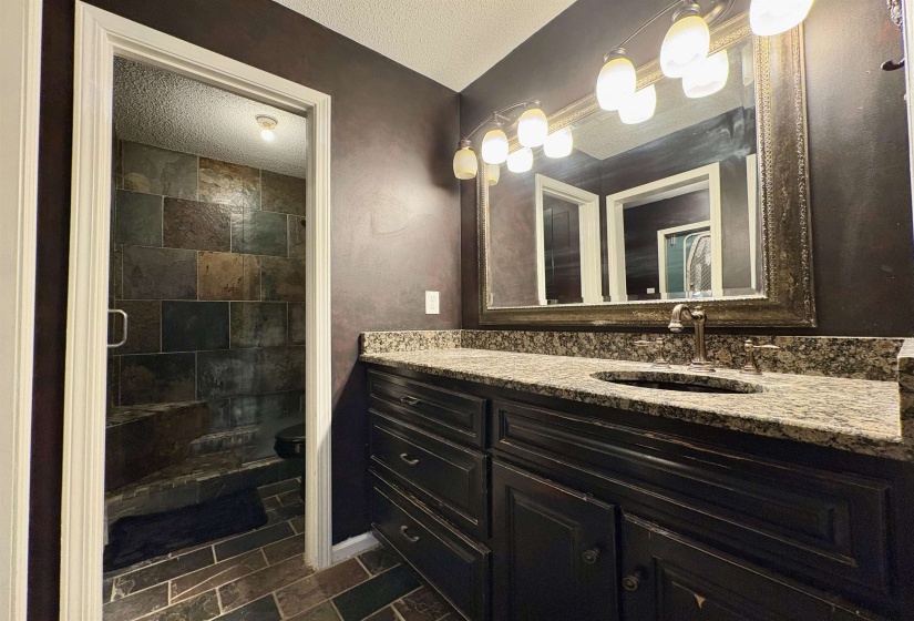 Full bath with vanity, a textured ceiling, and a stall shower