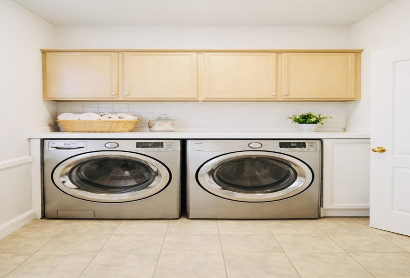 Laundry room with cabinet space, washing machine and clothes dryer, and light tile patterned floors