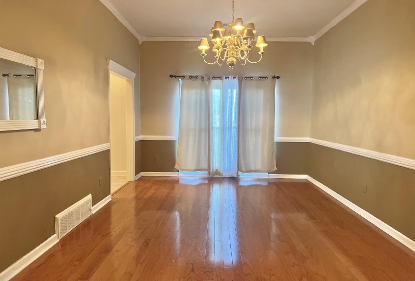 Empty room with a chandelier, ornamental molding, and wood finished floors