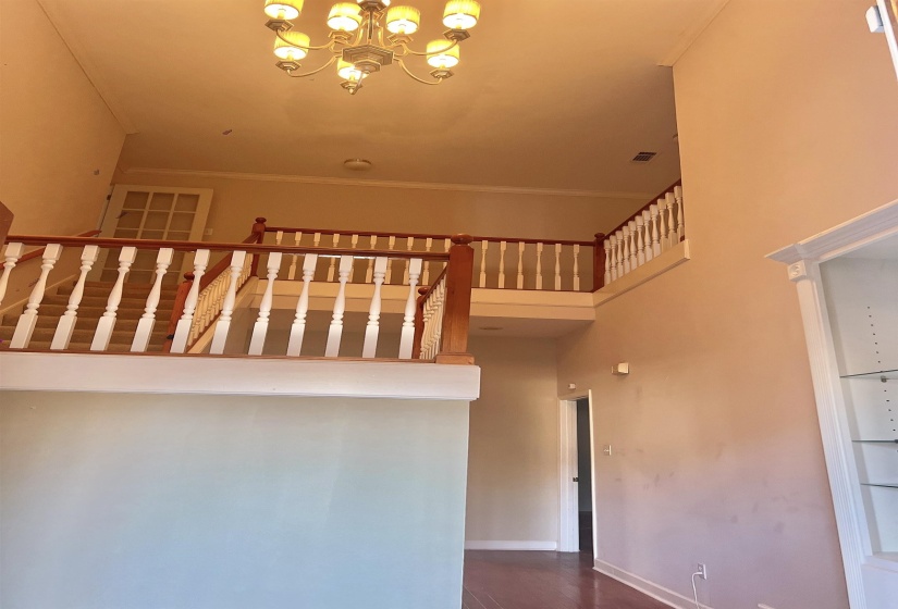 Stairs featuring a towering ceiling, a chandelier, wood finished floors, and crown molding