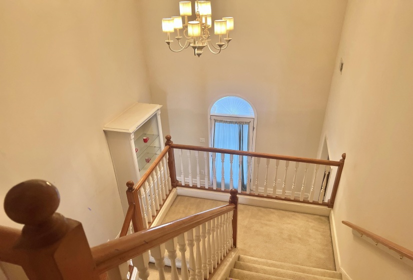 Stairs with a high ceiling, carpet floors, and a chandelier