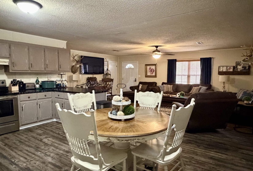 Dining area with a textured ceiling, dark wood-style floors, and ceiling fan