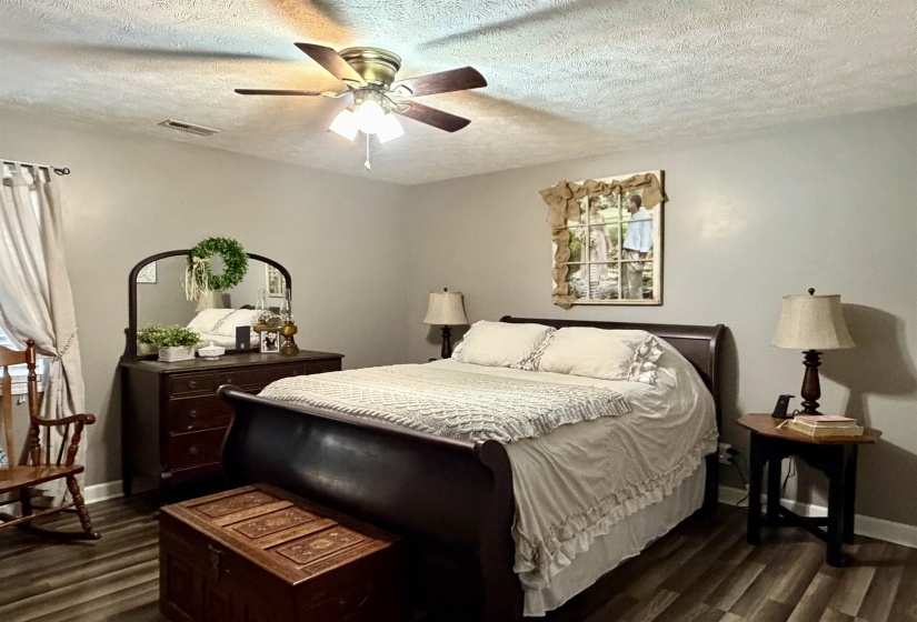 Bedroom with a textured ceiling, dark wood-style flooring, and ceiling fan
